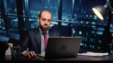 Information security officer finishing digitalization work in professional data center with mainframe servers. Male technician working in digital storage server room with artificial intelligence.