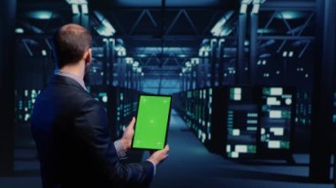 Database admin analyzing greenscreen display on tablet, doing web system check in server room. IT engineer using mockup copyspace display with isolated chroma key. Tripod shot.
