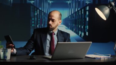 Information security officer answering phone call in server room, using big data and hardware for cloud computing in database center. Administrator working on cyberspace system, IT industry.