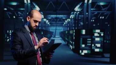 IT engineer using tablet in high tech server room, planning networking computer system. Database admin activating hardware server in data center, mainframe computer processor storage.