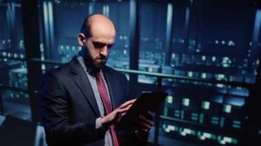 Tablette güvenlik taraması yapan bilişim yöneticisi, bilgisayar işlemcisi büyük verilerle ağ hizmetlerini denetliyor. Veri merkezinde sunucu raf kalitesini kontrol eden genç destek uzmanı.
