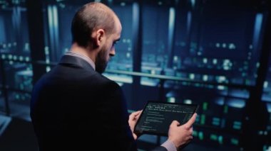 IT support specialist working with hosting server using tablet in professional data center, planning web digitalization. Male database admin inspecting system hardware in networking industry.