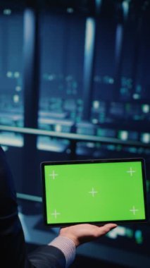 Vertical video: IT administrator running greenscreen display on tablet, using cloud computing in render farm. System technician working with isolated template and chroma key copyspace, artificial
