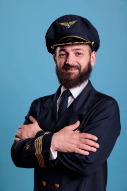 Aircraft aviator standing in professional uniform portrait, confident airplane captain standing, looking at camera, studio medium shot, side view. Civil pilot with badge on jacket