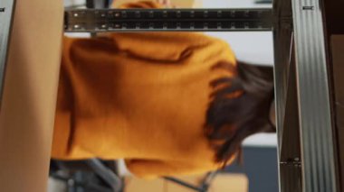 Vertical video: Team of asian workers using laptop to plan shipment, checking quality of goods in warehouse. Depot employees packing products in boxes for order management, financial planning.