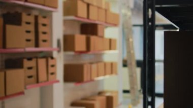 Storage room filled with boxes on racks and shelves, merchandise stock and cargo packages in warehouse. Manufacturing supplies packed in big containers, pallets in storehouse space. Handheld shot.