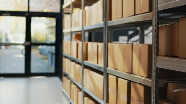 Empty storage room with packages on depot racks, containers and carton boxes prepared for stock distribution and order shipment. Warehouse space with retail store merchandise.