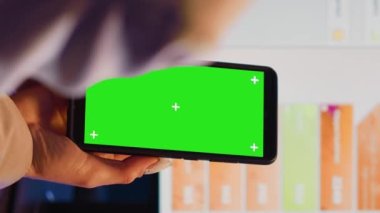 Vertical video: Advisor agent using mobile phone with green screen to work on corporate development. Professional manager analyzing isolated copyspace template, blank mockup chromakey display.