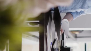 Vertical video: Professional employee analyzing company data on files, working with investment plan for successful growth. Female worker checking analytics and statistics on papers, annual report.