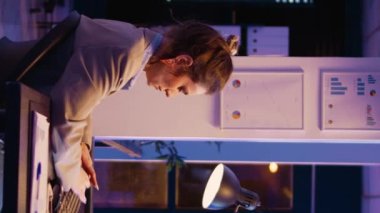 Vertical video: Entrepreneur working on financial growth late at night, planning business report with online statistics to finish project. Female advisor checking analytics after hours. Handheld shot.