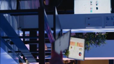 Dikey video: Girişimci bilgisayarla ilgili mali raporu kontrol ediyor, mesai sonrası ekonomi diyagramları üzerinde çalışıyor. Ofis çalışanı şirket alanına iş büyümesi ve kar yatırımı planlıyor.