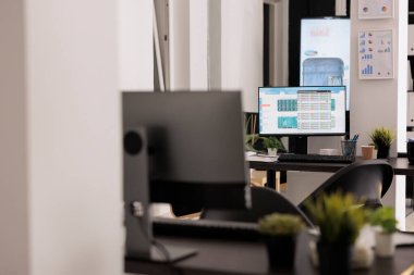 Workplaces with display computers on wooden table in a modern coworking space. Office with electronic device on empty desks before staff arrives to work, indoor working concept.