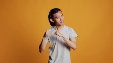 Male model having argument and acting violent, being furious and aggressive in studio. Young asian guy clenching fists on camera, showing violence and aggression. Rebel causing attack.