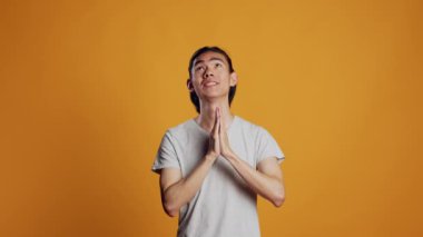 Mutlu Asyalı adam dua eden elleri imzalıyor ve pozitif davranıyor, kamera önünde ruhani ve neşeli oluyor. Genç umutlu adam dua ediyor ve dileğini yerine getirmek istiyor, inanç ve mutluluk gösteriyor..
