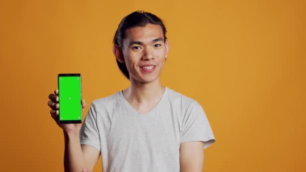 Ασιατικό Ανδρικό Μοντέλο Που Δείχνει Smartphone Πράσινη Οθόνη Στην Κάμερα — Αρχείο Βίντεο