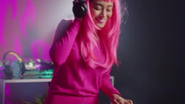 Smiling dj performing electronic music at party in nightclub, enjoying dancing and having fun with fans during performance. Asian musician mixing sound using professional mixer console