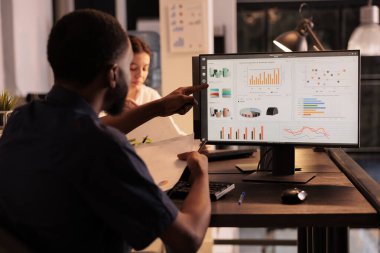 Analyst looking at marketing report data on computer, holding clipboard, employee comparing company research results in coworking space. African american businessman checking statistics in office