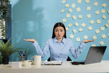 Portrait of a confused woman raising shoulders and making dont know gesture, looking puzzled and unsure. Doubtful female company employee not understanding what is going on.