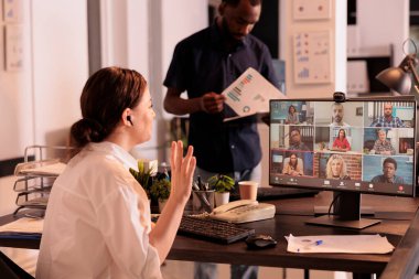 Woman talking with colleagues on online group chat, greeting coworkers, waving hi. Company employee discussing startup plan on webcam meeting, attending corporate videocall, telecommuting