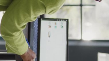 Vertical video: Business woman looking at annual report on laptop, planning corporate investment for marketing development. Startup worker checking data analytics on pc, taking notes on documents.