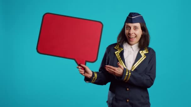 一个积极的女人拿着红色的语音泡沫在相机上 在商业航班的广告演播室工作 空姐微笑 在纸板箱上显示空白复制空间 从事航空业工作 — 图库视频影像