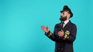 Erkek havacı kamera karşısında alkışlıyor ve tezahürat yapıyor. Tebrik ediyor ve stüdyoda el çırpıyor. Uçan üniformalı pilot neşeli duygularıyla ayakta alkışlıyor..