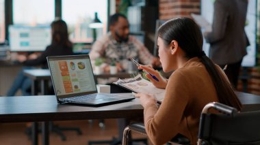 Özürlü bir ofis çalışanı dizüstü bilgisayardaki iş çizelgelerini analiz ediyor, büyüme stratejisi planlıyor. Bilgisayar ekranında finansal liderlik analizi oluşturmak için çalışan kadın yönetici.