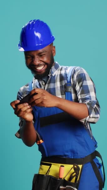 Vertical Video Confident Repairman Playing Mobile Video Games Blue Background — Video