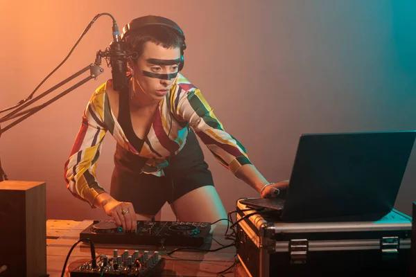 Musical performer using turntables to mix techno music, producing sounds at dj mixer with electronics and bass key. Woman working as artist doing remix performance at nightclub in studio.