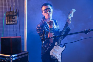 Cool artist blowing air kisses and acting flirty, playing guitar and having heavy metal style in studio. Sending kiss and being romantic or charming, singing alternative rock music with instrument.