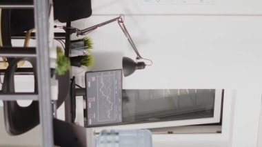 Vertical video: Professional corporation workstations with multiple desks, empty open space filled with boardroom business equipment and computers. Digital agency workspace in corporate interior.