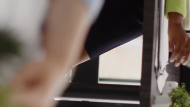 Vertical video: Agency entrepreneur thinking about growth solution to increase company profit at workplace. Young assistant brainstorming new ideas to create executive report for business development.