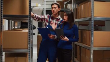 Group of asian people working in storage room with packs, doing financial planning with digital tablet and papers. Young man and business owner talking about supply chain management.