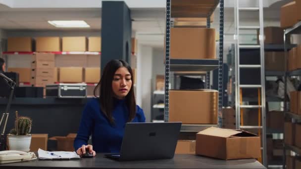 亚洲企业主致力于商品库存在箱子里的创业发展 计划在储藏室装运 使用笔记本电脑规划质量控制和盘存的年轻人 — 图库视频影像