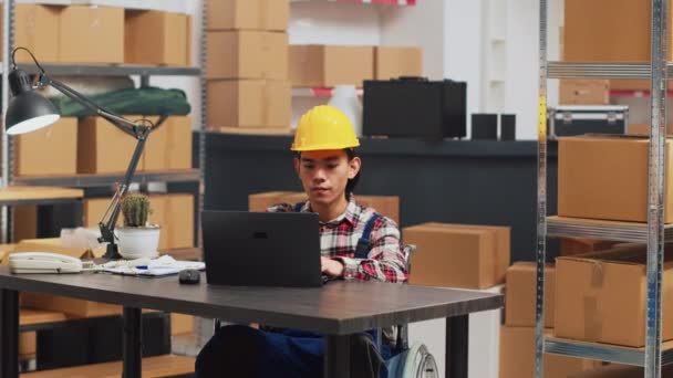 坐在轮椅上的亚洲人在笔记本电脑上工作 编制预算 将库存货物用于商业发展 残疾工人在储藏室组织产品 计划装运 — 图库视频影像