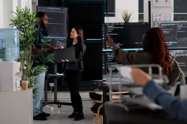 Software engineers discussing about algorithms on big screen and laptop, analyzing html script language. Team of system programmers discussing database on terminal window, server interface.