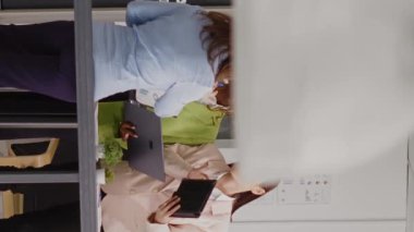 Vertical video: Diverse group of people analyzing online data at desk and using research plan with analytics for investment. Female employees discussing new business ideas in executive briefing