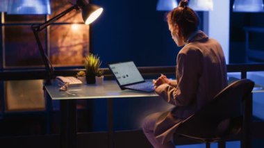 Executive manager analyzing economy graphs on screen, working at night in financial company office. Woman employee planning growth report for management in startup space, typing statistics.