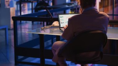 Female employee planning corporate analytics at night, working late in office to create financial report. Caucasian businesswoman analyzing financial investment to work on profit growth.