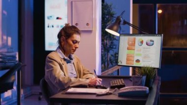 Executive manager analyzing graphs on report, working after hours on investment plan in business office. Young corporate advisor planning company growth and development, increase profit.