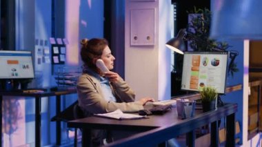Ofisteki ekonomi istatistiklerinin diyagramlarını inceleyen bir iş kadını. Finansal analizlerle çalışan şirket çalışanı telefon hattında rapor veriyor..