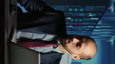 Vertical video: Information security officer answering phone call in server room, using big data and hardware for cloud computing in database center. Administrator working on cyberspace system, IT