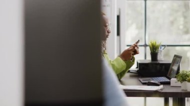 Afrika kökenli Amerikalı bir işçi ara verildiğinde akıllı telefon uygulaması kullanarak sosyal medya sitesini kontrol ediyor. Yönetici internet tarayıcısına cep telefonundan bakıyor, büyüme için yeni yatırım planlıyor.