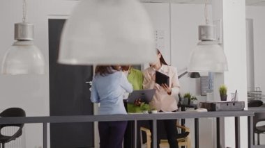 Diverse group of people analyzing online data at desk and using research plan with analytics for investment. Female employees discussing new business ideas in executive briefing meeting.