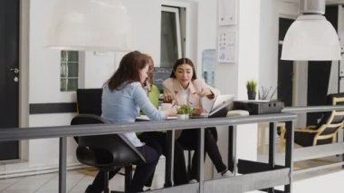 Multiethnic group of employees discussing new strategy for business development in coworking space. Professional women thinking about corporate investment to increase profit in office.
