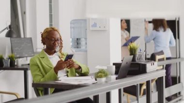 Business woman checking mobile phone app, navigating through social media in agency workplace. Female manager taking break with smartphone, creating annual report. Tripod shot.