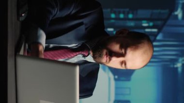 Vertical video: System administrator working in data center render farm, creating cloud computing service for innovation and digitalization. Database admin using big hardware data in server room.