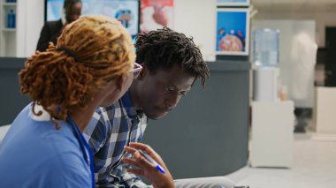 Hemşire, erkek hastaya teşhisi açıklıyor. Hastane bekleme odasında check-up formlarını gösteriyor. Genç yetişkinler hastalık ve tedavi hakkında uzmanlarla konuşuyor, danışmanlık yapıyorlar..