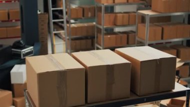 Warehouse filled with raw materials and racks to put cardboard boxes, preparing packages with merchandise and products for shipping. Empty storage room used for quality control, small business.