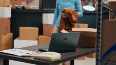 Young adult using merchandise from warehouse to prepare order, shipping products before doing inventory. Female employee planning distribution management, woking on business development.